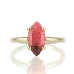 May include: A gold ring with a marquise-shaped pink gemstone.