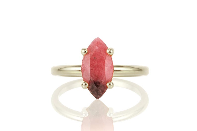 May include: A gold ring with a marquise-shaped pink gemstone.