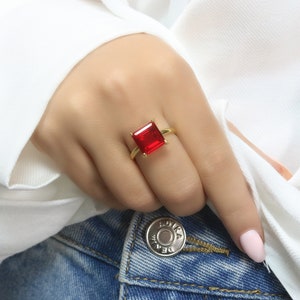 Puede incluir: Un anillo de oro con una piedra roja cuadrada grande.