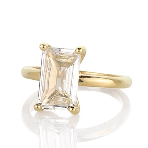 May include: A gold ring with a large, clear, emerald-cut gemstone.