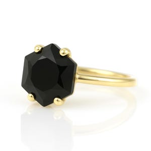 May include: A gold ring with a black octagonal gemstone. The ring is simple and elegant.