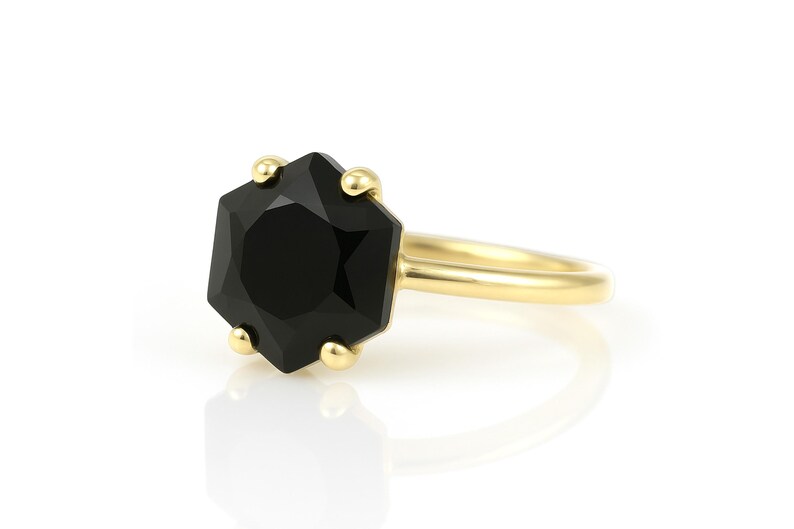 May include: A gold ring with a black octagonal gemstone. The ring is simple and elegant.