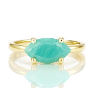 K&ouml;nnte beinhalten: Ein goldener Ring mit einem gr&uuml;nen Edelstein in Marquise-Form. Der Edelstein ist in einer Krappenfassung gefasst und hat eine glatte, polierte Oberfl&auml;che.
