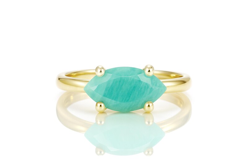 K&ouml;nnte beinhalten: Ein goldener Ring mit einem gr&uuml;nen Edelstein in Marquise-Form. Der Edelstein ist in einer Krappenfassung gefasst und hat eine glatte, polierte Oberfl&auml;che.
