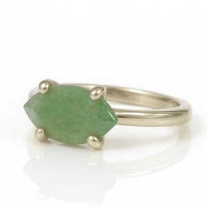 May include: A gold ring with a green marquise-shaped gemstone set in the center.