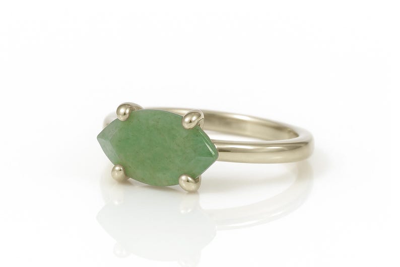 May include: A gold ring with a green marquise-shaped gemstone set in the center.