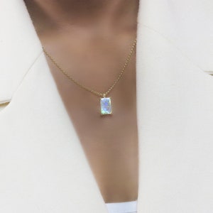 May include: A gold chain necklace with a rectangular iridescent gemstone pendant.