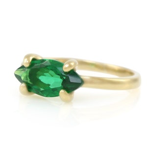 Puede incluir: Un anillo de oro con una piedra preciosa verde en forma de marquesa.