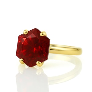 May include: A gold ring with a large, red, octagonal gemstone.