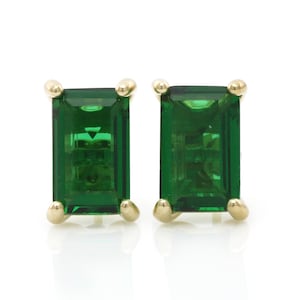 May include: A pair of gold earrings with emerald green rectangular gemstones.