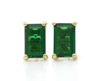 Pode incluir: Um par de brincos de ouro com pedras retangulares de cor verde esmeralda.