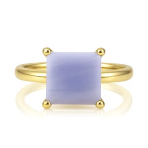 May include: A gold ring with a square, light blue gemstone. The ring is set with small gold beads around the gemstone.