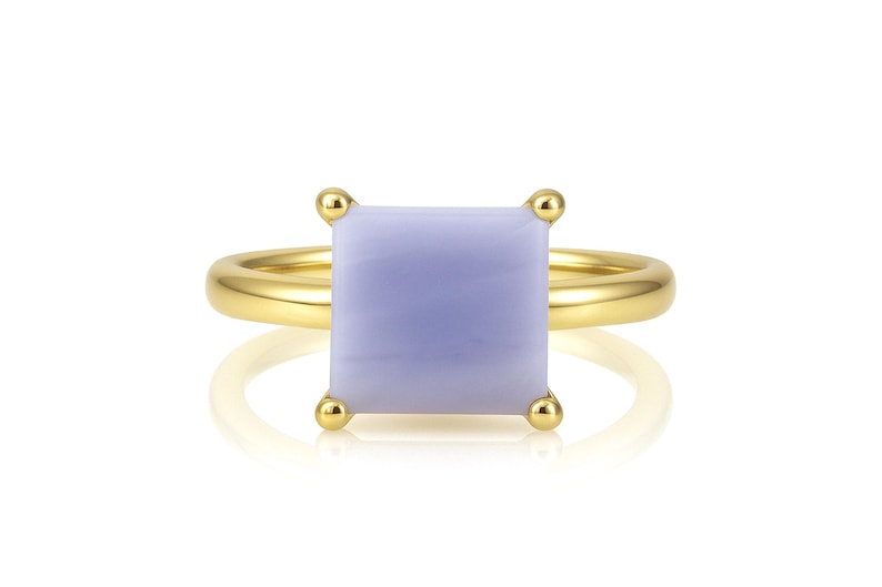 May include: A gold ring with a square, light blue gemstone. The ring is set with small gold beads around the gemstone.
