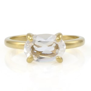 May include: A gold ring with a clear oval-shaped gemstone.