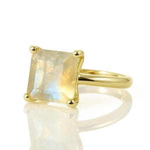 May include: A gold ring with a square-shaped moonstone gemstone.