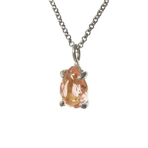 May include: A silver chain necklace with a pear-shaped pendant featuring a light pink and orange gemstone.