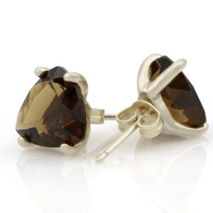 May include: A pair of silver stud earrings with brown heart-shaped gemstones.