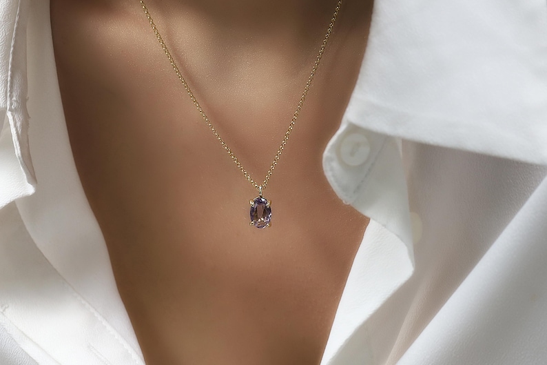 May include: A gold chain necklace with a purple oval gemstone pendant.