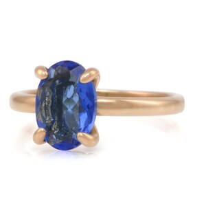 Op de afbeelding: Een gouden ring met een grote ovale blauwe edelsteen.