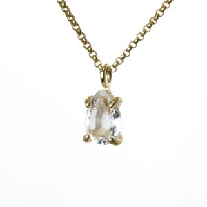 May include: A gold chain necklace with a clear pear-shaped gemstone pendant.