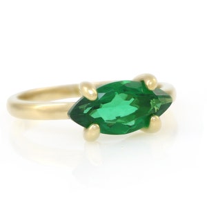 Puede incluir: Un anillo de oro con una piedra preciosa verde en forma de marquesa.