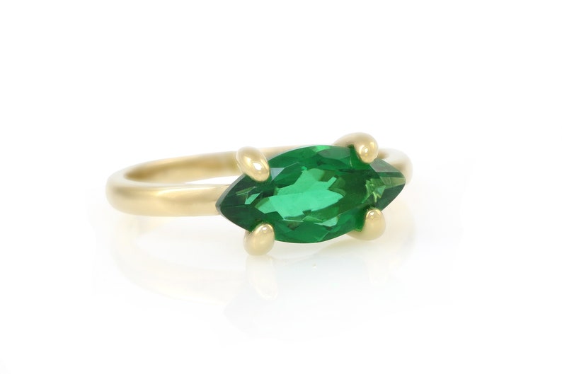 Puede incluir: Un anillo de oro con una piedra preciosa verde en forma de marquesa.