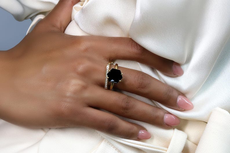 May include: A gold ring with a large black gemstone and a smaller band of diamonds set in gold.