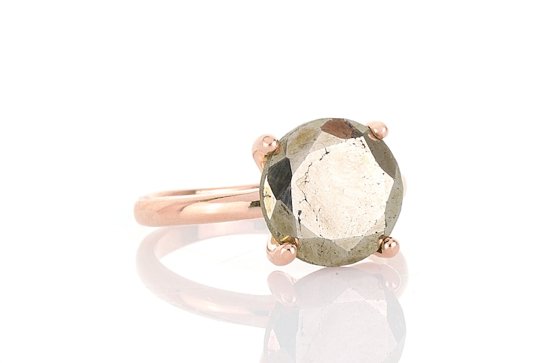 May include: A rose gold ring with a large, faceted, gray gemstone.