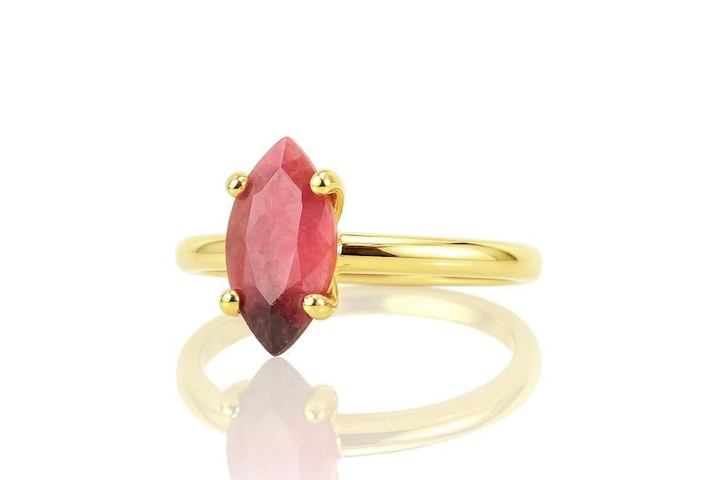 May include: A gold ring with a pink and red marquise-shaped gemstone.