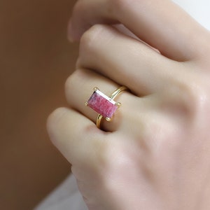 May include: A gold ring with a pink and white rectangular gemstone.
