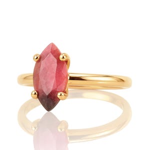 May include: A gold ring with a pink and red marquise-shaped gemstone.
