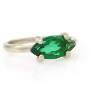 Puede incluir: Un anillo de plata con una piedra preciosa verde en forma de marquesa.