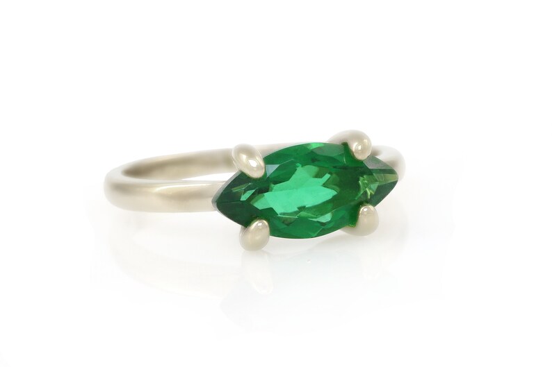 Puede incluir: Un anillo de plata con una piedra preciosa verde en forma de marquesa.