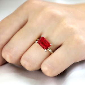 May include: A gold ring with a large, rectangular, red gemstone.