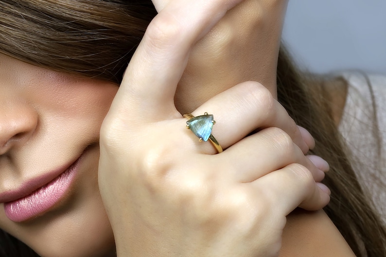 May include: A gold ring with a triangular iridescent blue gemstone.