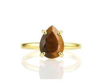 Op de afbeelding: Een gouden ring met een traanvormige tijgeroog-edelsteen.