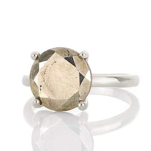 May include: A silver ring with a large, faceted, round, gold-toned gemstone.