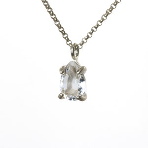 May include: A silver chain necklace with a clear pear-shaped gemstone pendant.