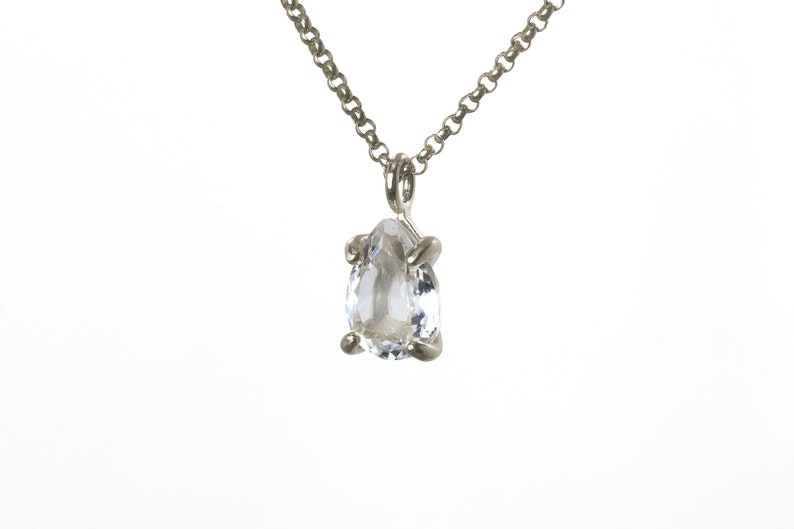 May include: A silver chain necklace with a clear pear-shaped gemstone pendant.