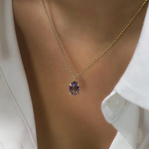 May include: A gold chain necklace with a purple oval gemstone pendant.