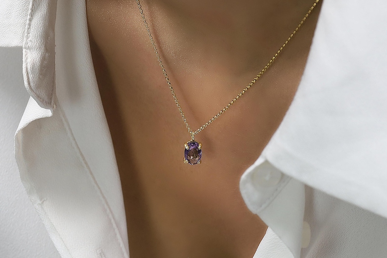 May include: A gold chain necklace with a purple oval gemstone pendant.