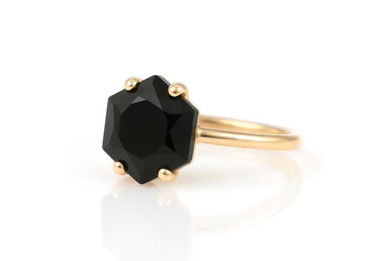 May include: A gold ring with a black octagonal gemstone. The ring is simple and elegant.