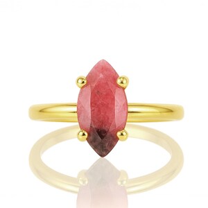 May include: A gold ring with a pink and red marquise-shaped gemstone.