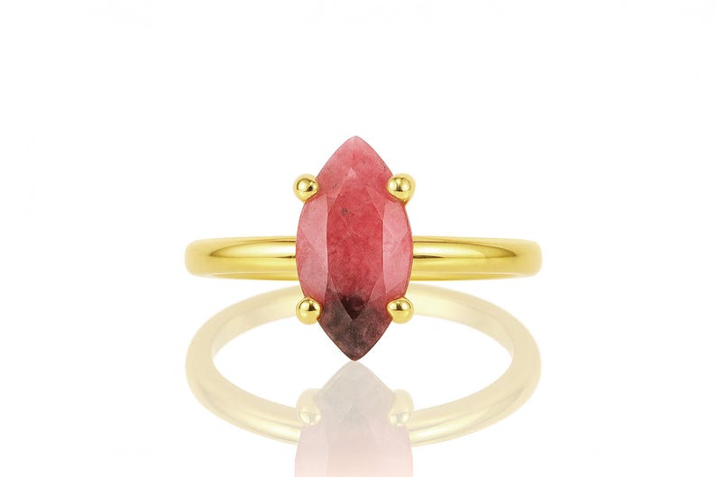 May include: A gold ring with a pink and red marquise-shaped gemstone.