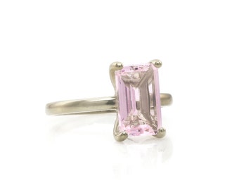 May include: A silver ring with a pink emerald-cut gemstone.