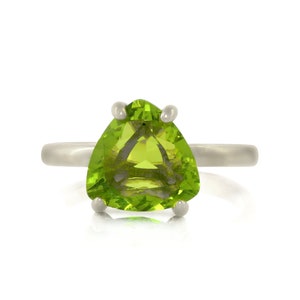 May include: A silver ring with a triangular green peridot gemstone.