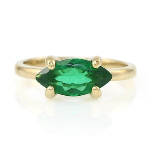Puede incluir: Un anillo de oro con una piedra preciosa verde en forma de marquesa.