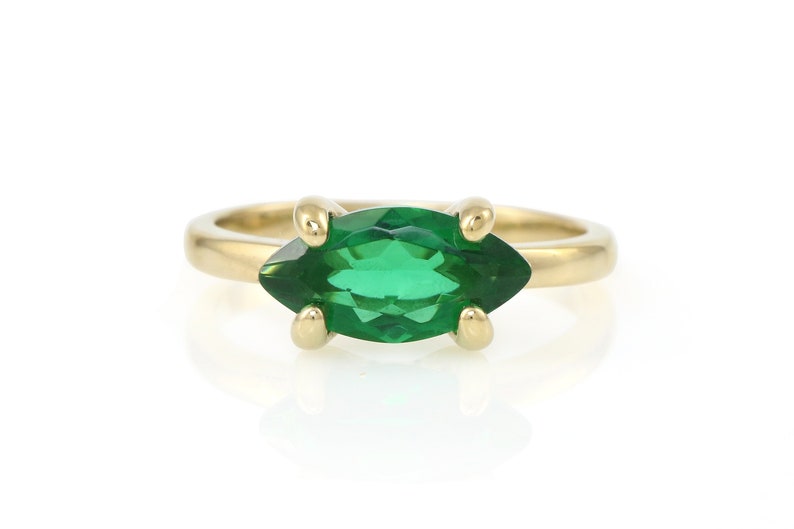 Puede incluir: Un anillo de oro con una piedra preciosa verde en forma de marquesa.