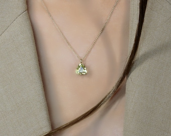 May include: A gold chain necklace with a pear-shaped light green gemstone pendant.