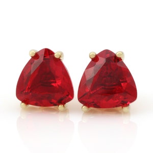 May include: A pair of gold earrings with red triangular gemstones.